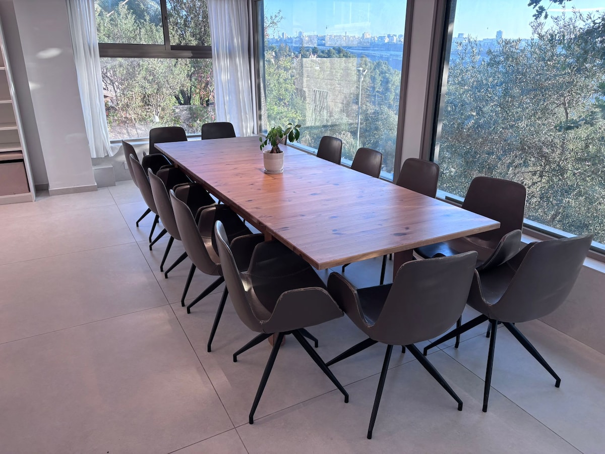 Dining table for thirteen beside panoramic windows overlooking Jerusalem’s hills